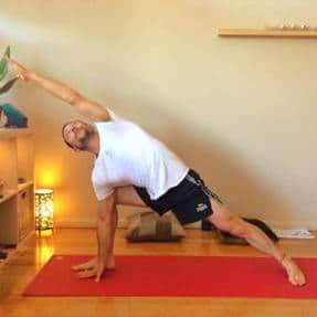 Man in tshirt and shorts doing side angle yoga pose 